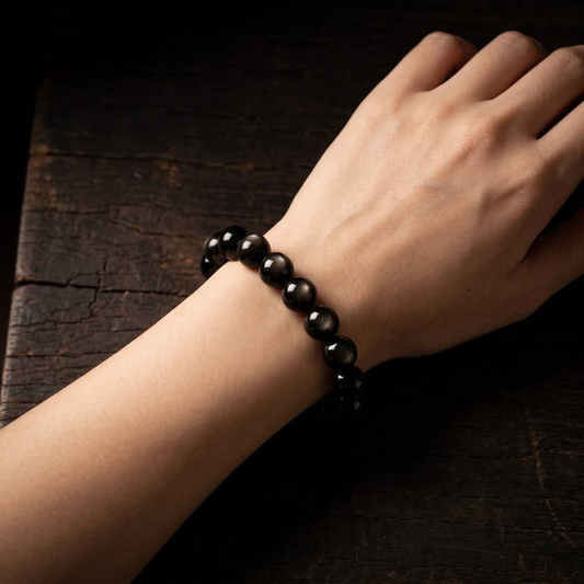 Natural 10mm obsidian bracelet with metallic sheen worn on the wrist