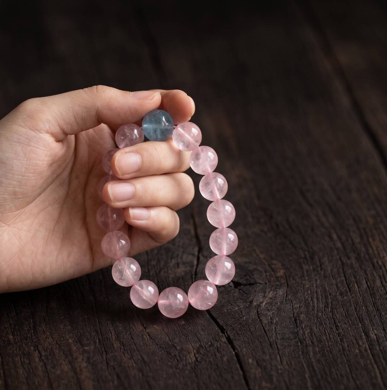 10mm rose quartz and aquamarine bracelet held in hand under natural light