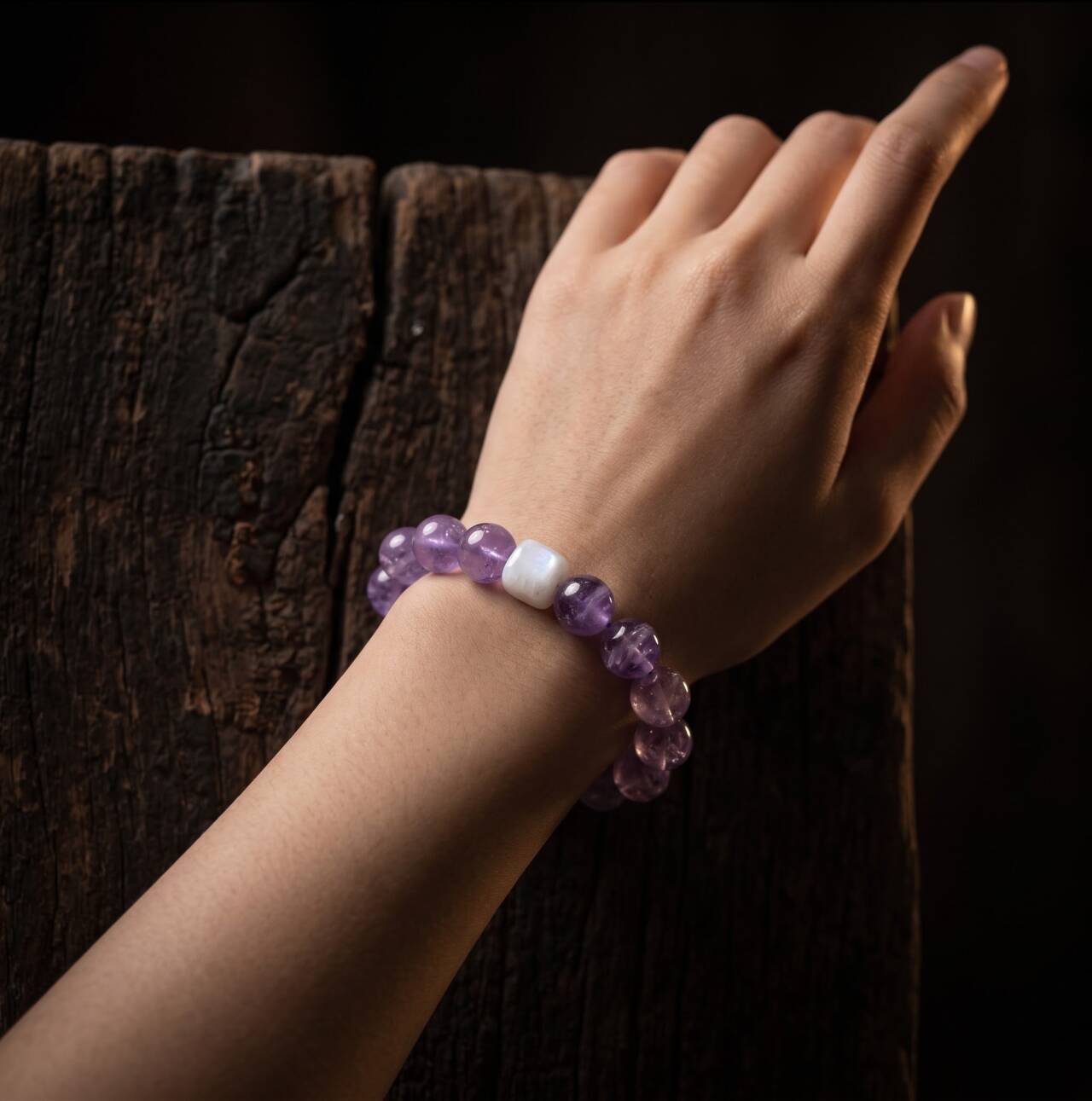 Hand-held view of a 10mm amethyst bracelet in natural light