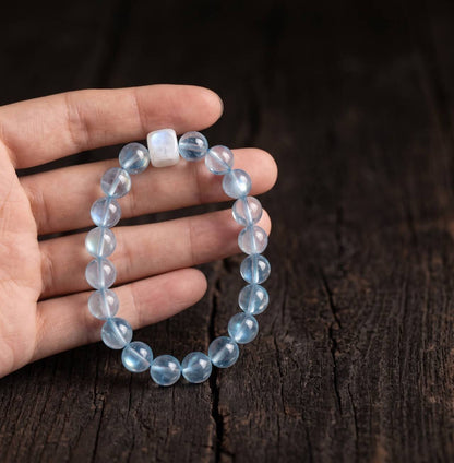 Clear blue 10mm aquamarine bracelet held in hand under natural light