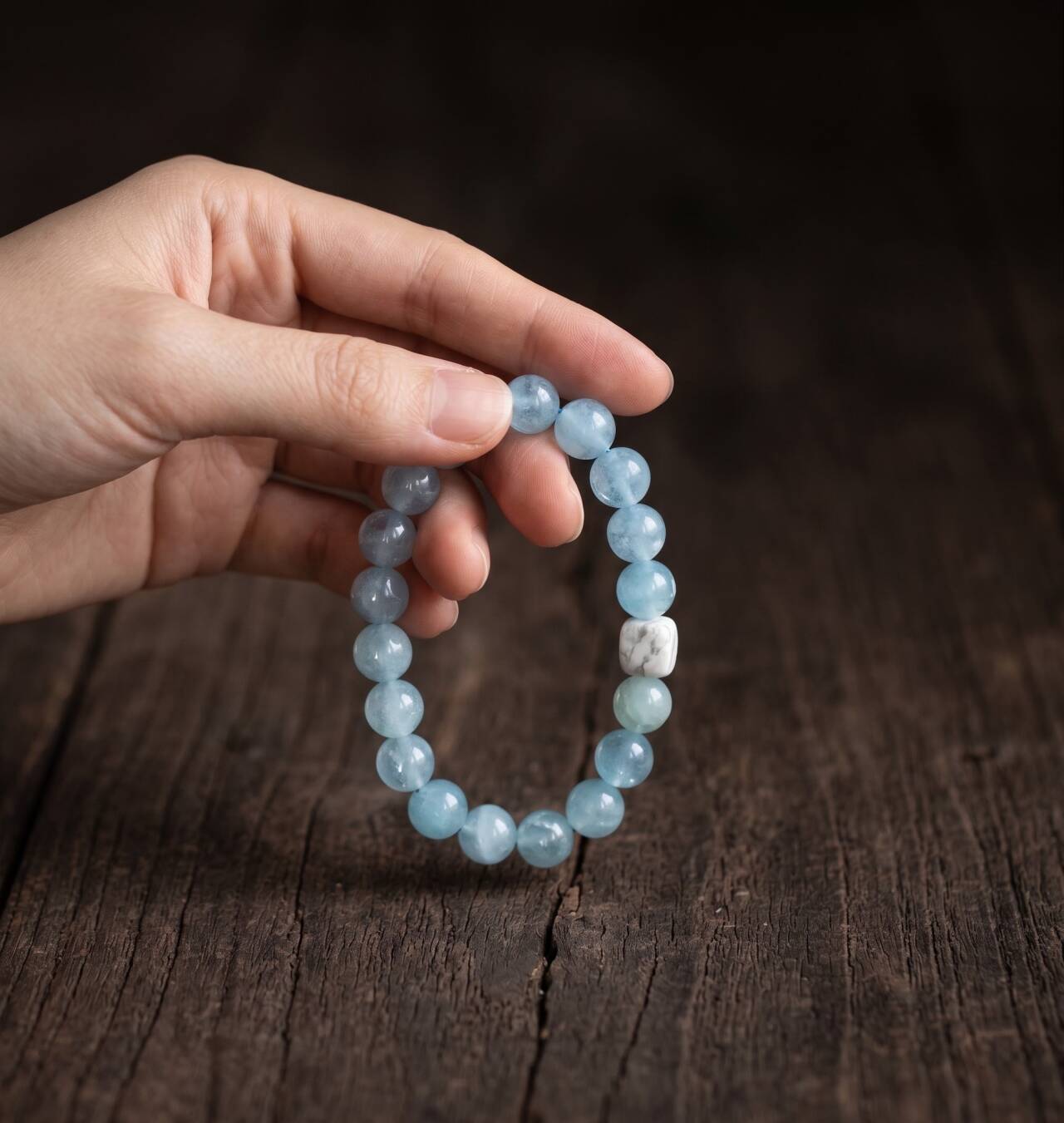 Misty aqua 10mm aquamarine bracelet held in hand under natural light