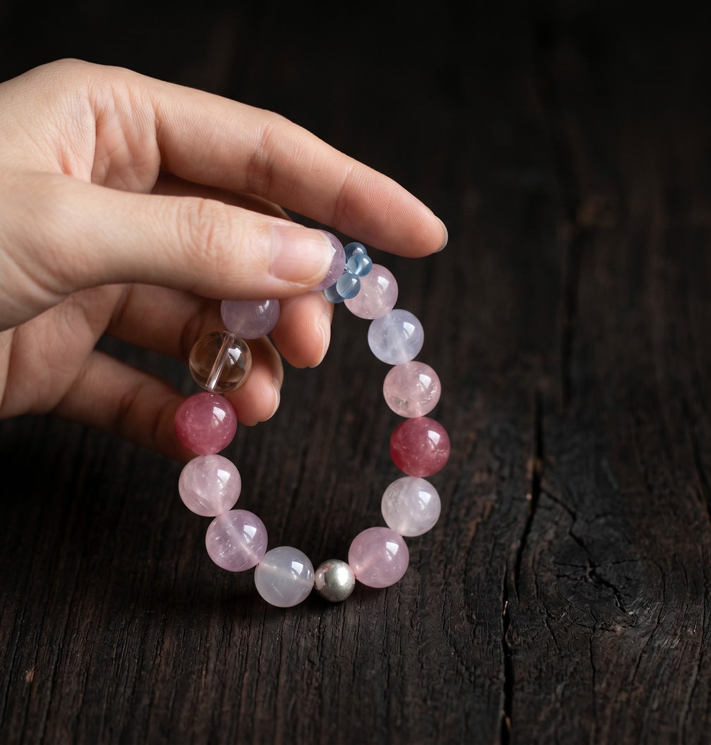 10mm clear-toned crystal and rose quartz bracelet held in hand