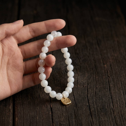 Natural 7mm Hetian jade bracelet held in hand against a dark background