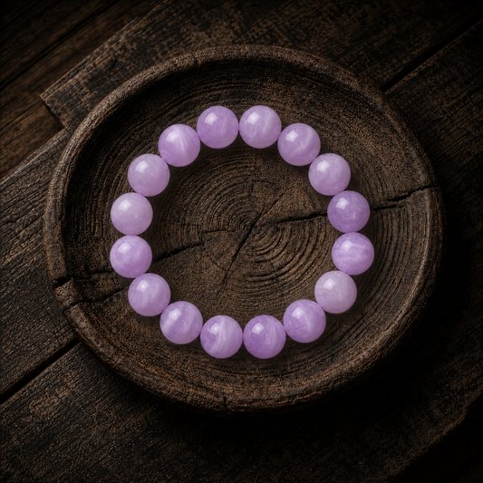 Natural kunzite bracelet in 10MM beads on a dark brown wood background
