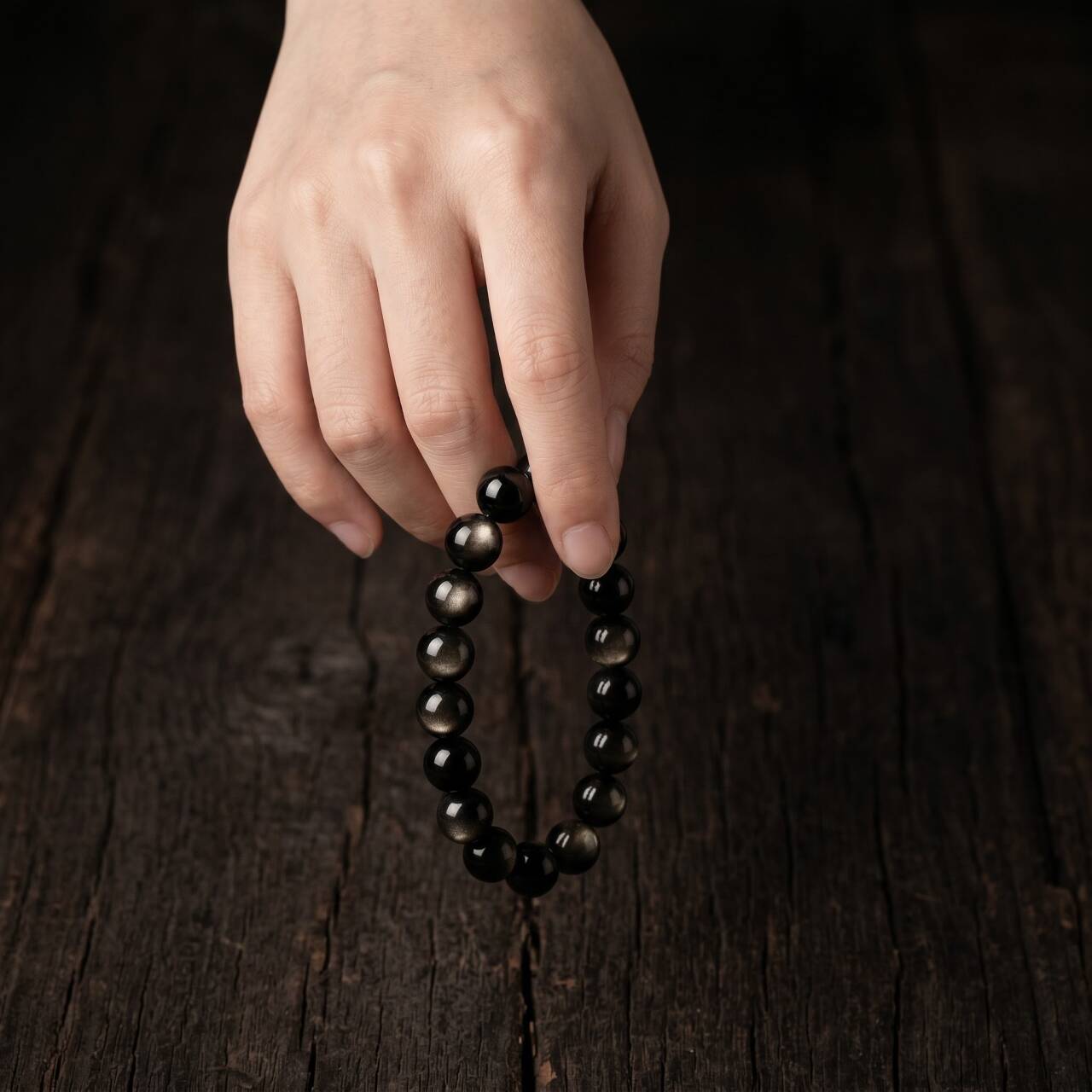 Natural 10mm obsidian bracelet held in hand under natural light
