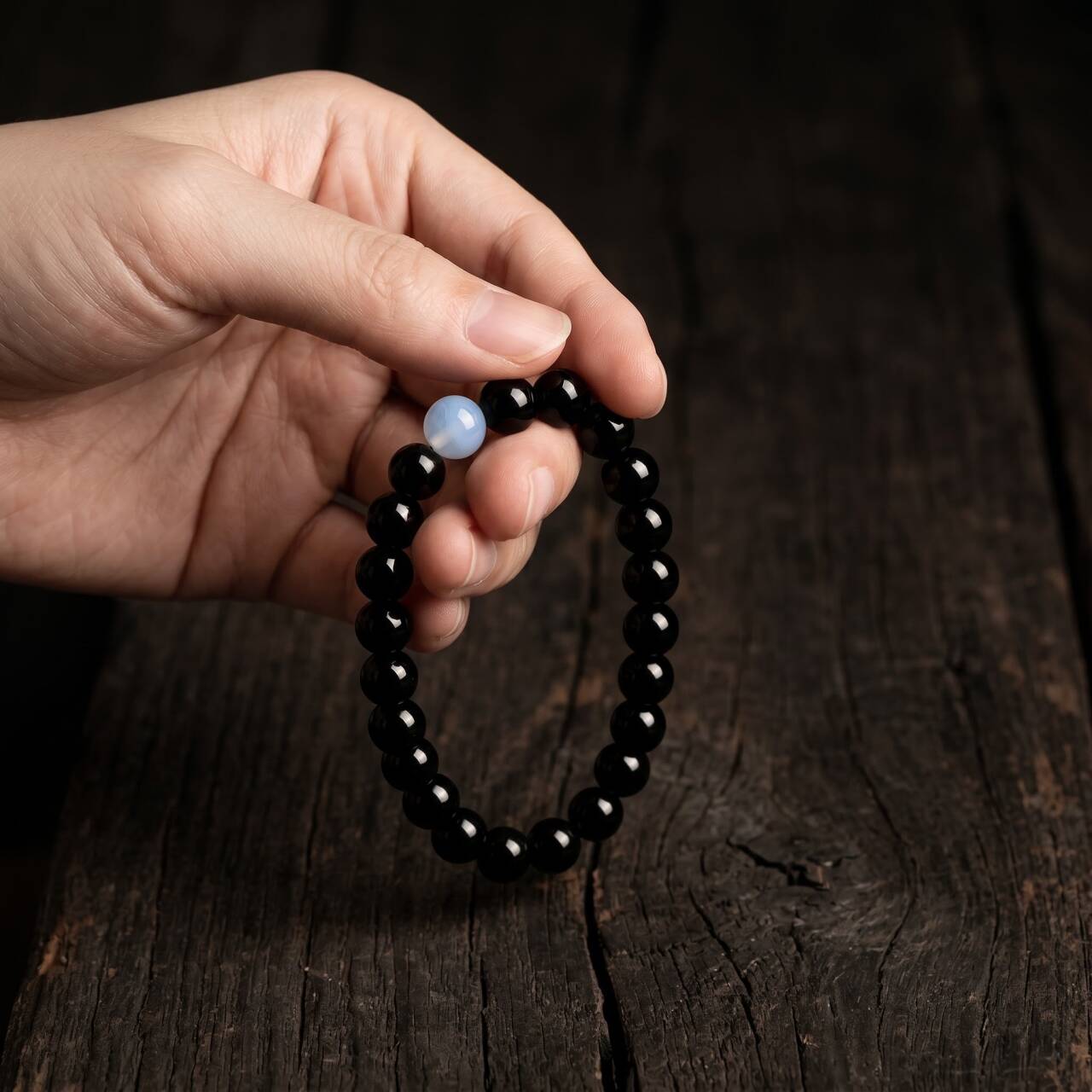 Hand-held view of a 10mm obsidian bracelet in natural light