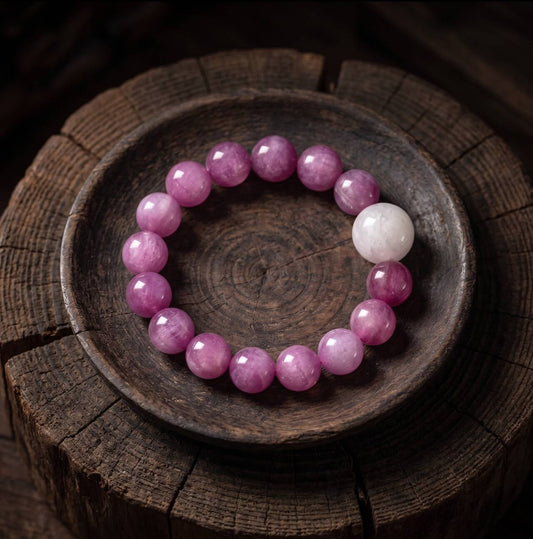 Purple 10mm round-bead bracelet with one pale bead arranged in a dark wooden bowl