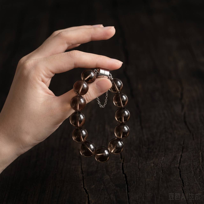 Smoky brown translucent 10mm bead bracelet held in one hand